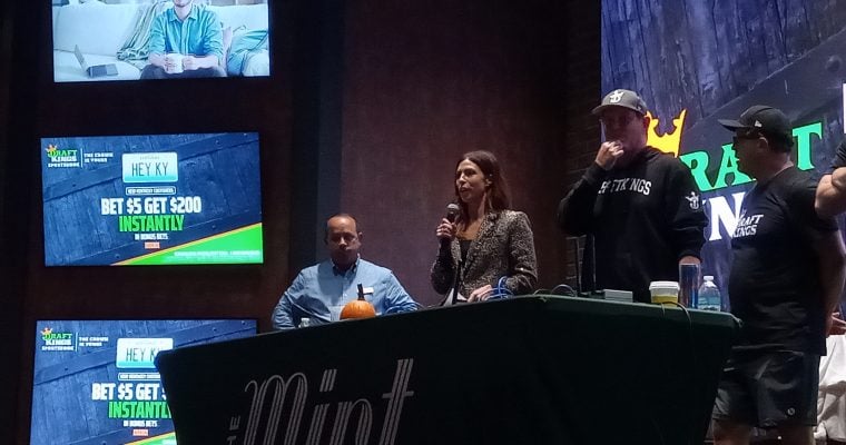 DraftKings Senior Director of Gaming Partnerships Krista Thomas speaks to the crowd at The Mint Cumberland mobile launch event Thursday. KSR host Matt Jones (right) and The Mint Cumberland General Manager Henry Graffeo (left) joined her on stage.