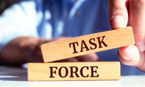 a pair of blocks that spell out task force being placed together by a hand