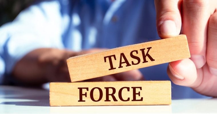 a pair of blocks that spell out task force being placed together by a hand