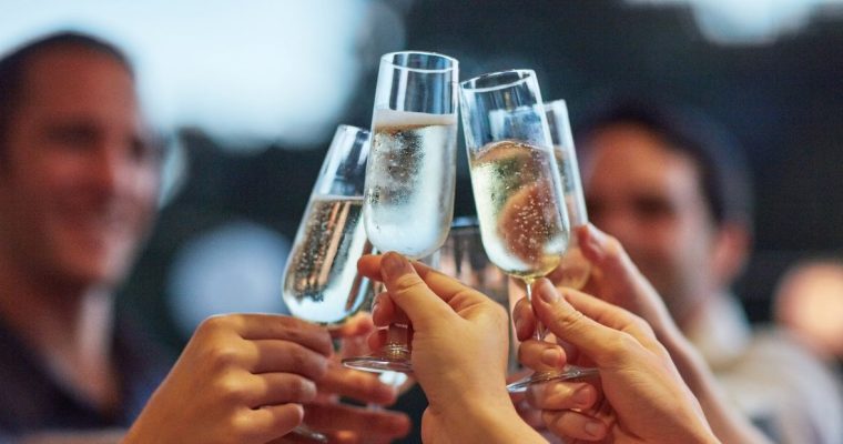 a group of people celebrating by cheering their champagne glasses