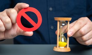 a person holding an hour glass and a ban symbol