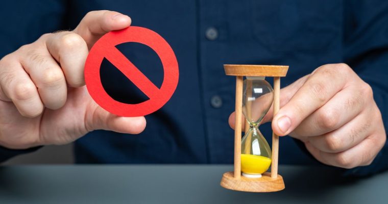 a person holding an hour glass and a ban symbol