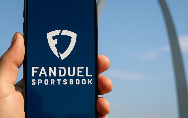 A realistic photo showing the St. Louis Gateway Arch at dusk with a smartphone displaying the FanDuel Sportsbook logo in the foreground.
