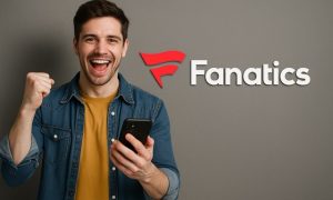 Man smiling while holding a smartphone in front of a large Fanatics Sportsbook logo on a clean, light background.