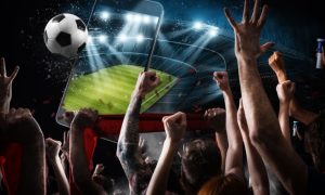 Image Collage with Cell Phone Displahying Soccer Field Hovering Above Crowd of Cheering Fans