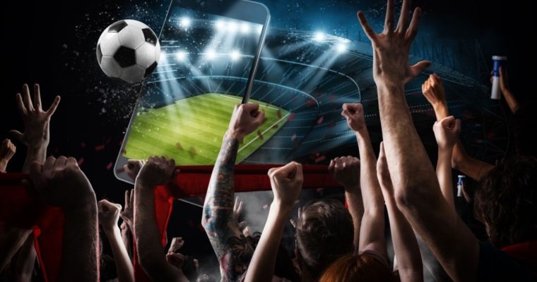 Image Collage with Cell Phone Displahying Soccer Field Hovering Above Crowd of Cheering Fans