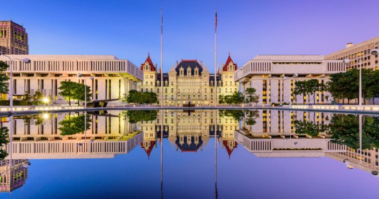 The New York State Capitol Building At Dusk is reflected in water Creating a Mirror Image