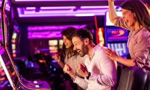 Purple-Hued Neon Lights Inside Casino with Three People Celebrating Slot Win