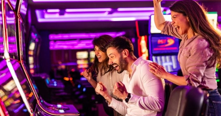 Purple-Hued Neon Lights Inside Casino with Three People Celebrating Slot Win