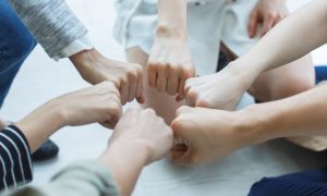 People Connect Fists In Circle Representing Peer Support Group