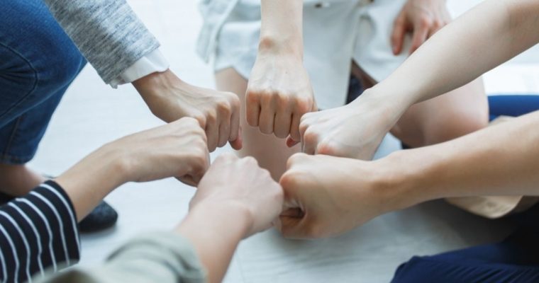 People Connect Fists In Circle Representing Peer Support Group