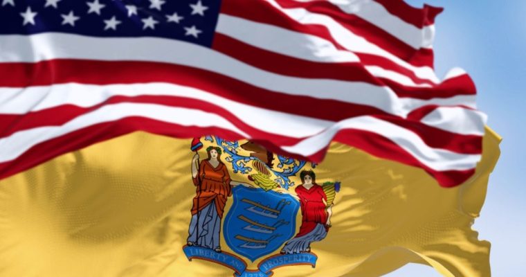 Close Up Image of Waving American Flag Above NJ State Flag Against Blue Sky