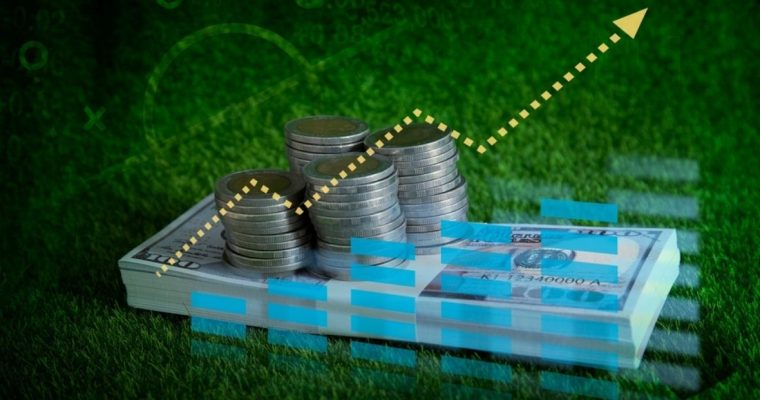 Financial Graph Digital Overlay on Stacks of Coins and Bills on Green Grass