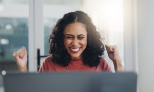Happy Woman Sits in Front of Laptop