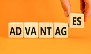 Man's Hand Holds Up Last Two Letters of "Advantages" Written on Wood Blocks