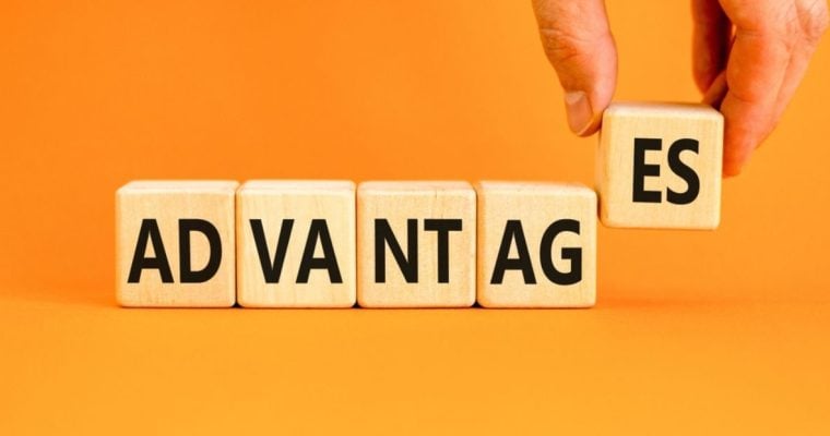 Man's Hand Holds Up Last Two Letters of "Advantages" Written on Wood Blocks