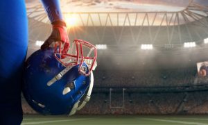Brightly-Lit American Football Stadium with Close Up Of Player's Hand Holding Blue and Red Helmet