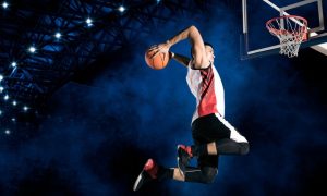 Male Basketball Player Set to Dunk Inside Smoky Blue Stadium
