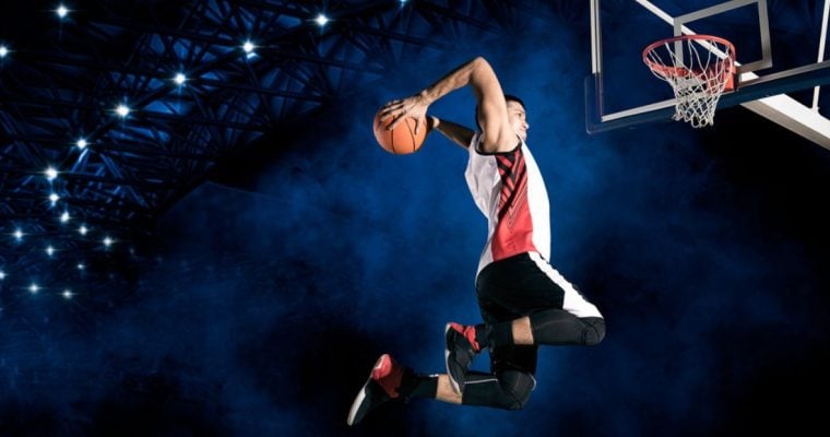 Male Basketball Player Set to Dunk Inside Smoky Blue Stadium