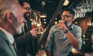 Three Men Drink Beer at a Bar Socializing