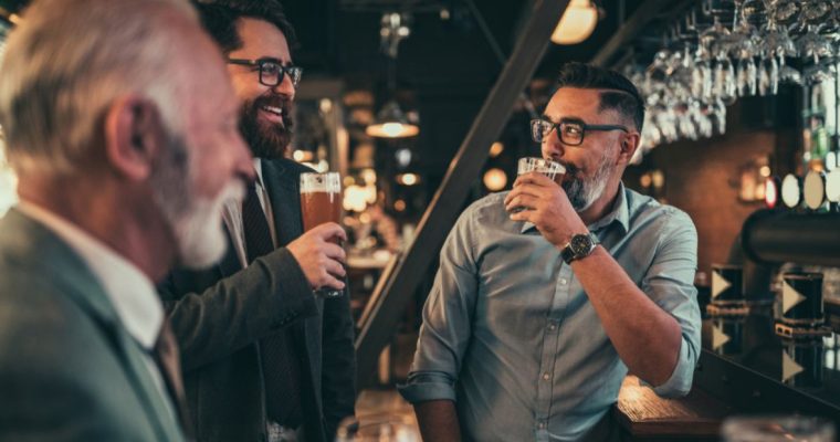 Three Men Drink Beer at a Bar Socializing