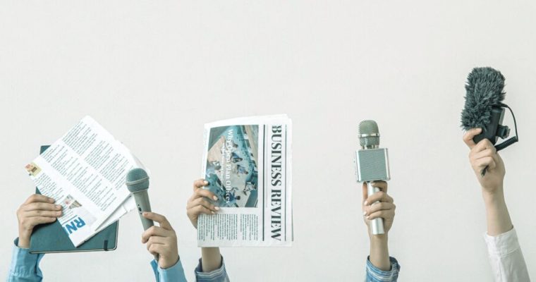 News Reporters Hold Up Microphones and Newspapers on Solid Background