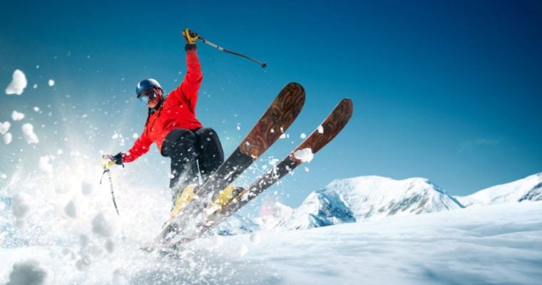 Man Jumping on Skiis From a Snowy Mountain Top