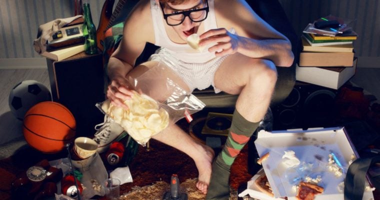 Man Glued to the TV Eats Chips From Bag In Messy House
