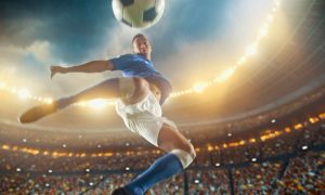 Soccer Player Jumps To Kick Ball Inside Filled Stadium