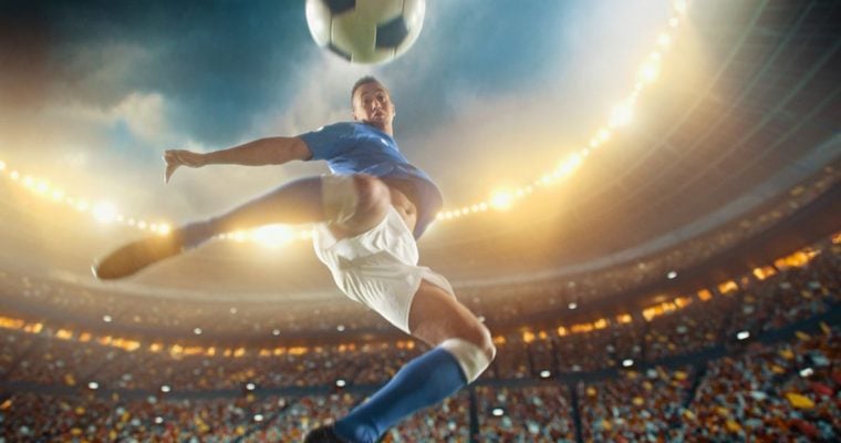 Soccer Player Jumps To Kick Ball Inside Filled Stadium