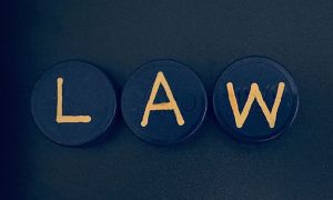Three Small Round Shapes With Gold Letters Spelling Out LAW on Black Background