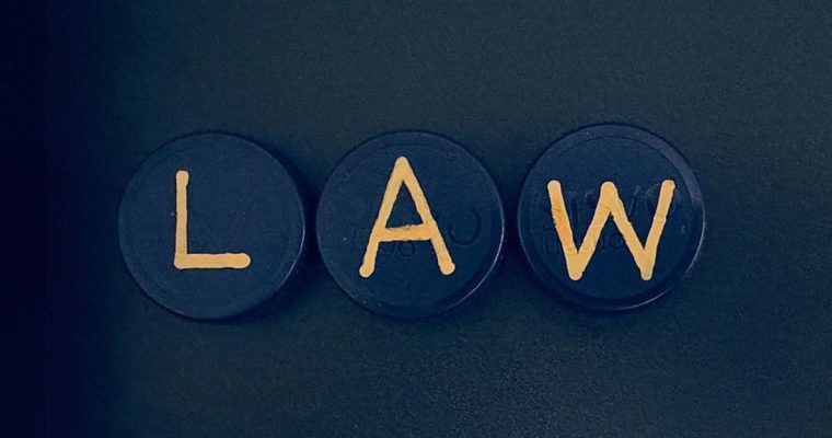 Three Small Round Shapes With Gold Letters Spelling Out LAW on Black Background