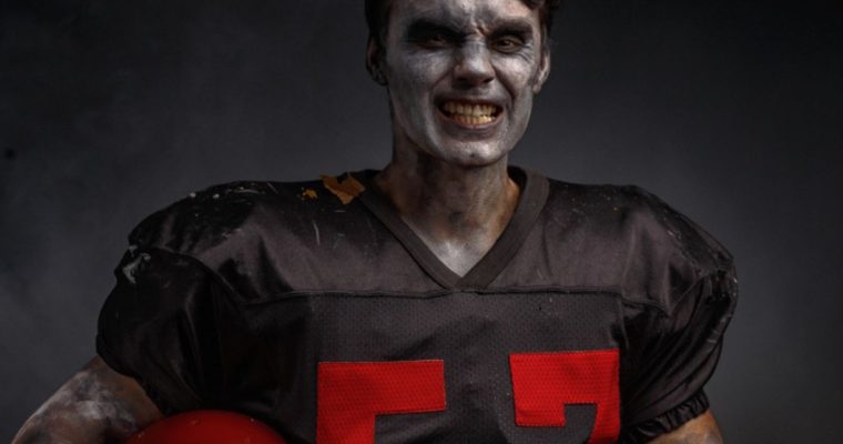 American Football Player In Zombie Makeup Wears Black Jersey with Red Numbers