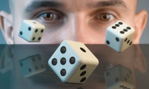 Close Up of Man's Brown Eyes Watching Three Dice Tumbling on Table