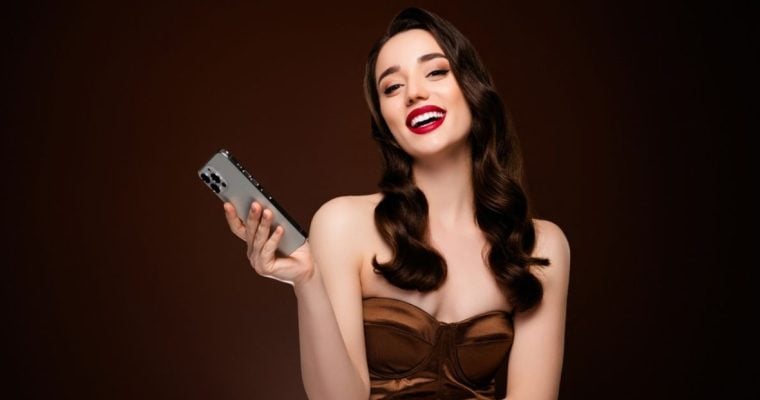 Smiling Brunette Holds Cell Phone on Brown Background