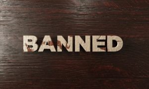 Word Banned Spelled Out in Light Wood Letters on Dark Wood Background