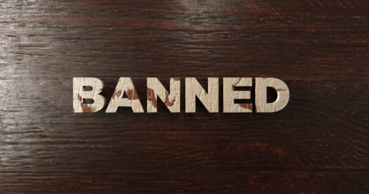 Word Banned Spelled Out in Light Wood Letters on Dark Wood Background