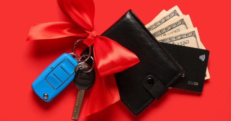 Red Bow on Car Keys Next To Black Wallet With $100 Bills Sticking Out