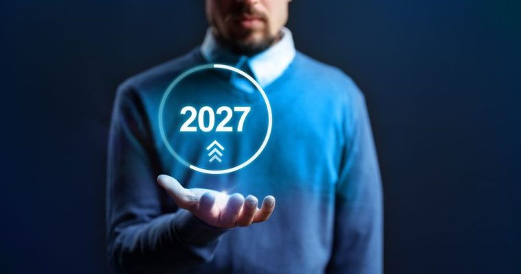 Man Wearing Blue Sweater with Digital Image Of 2027 Inside Circle Hovering Over His Open Palm