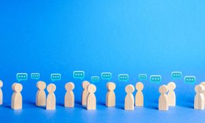 Wooden Human-Shaped Figures with Speech Bubbles on Blue Background