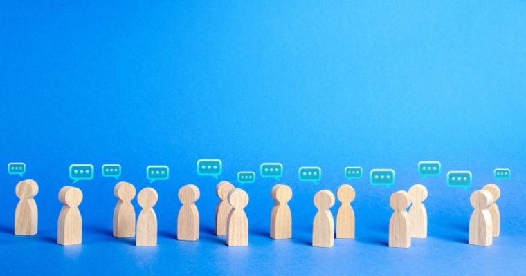 Wooden Human-Shaped Figures with Speech Bubbles on Blue Background