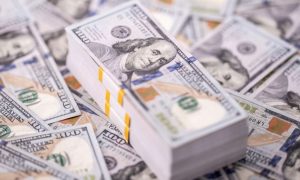 Large Stack of $100 Bills Sits On Top of Table Covered with More $100 Bills
