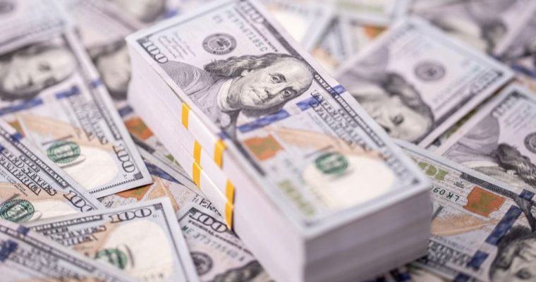 Large Stack of $100 Bills Sits On Top of Table Covered with More $100 Bills