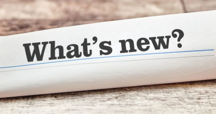 Rolled Up Newspaper on Wood Table Reads What's New?