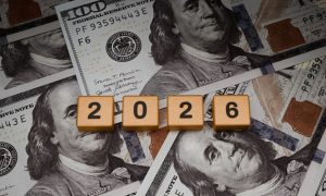 $100 Banknotes Layed On Table with Wooden Blocks Spelling 2026 on Top