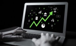 Black and White Image of Hands Using Laptop Displaying Bright Green Upward Trending Arrow and Economic Icons