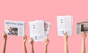 Four Sets of Hands Hold Up Newspapers Against Pick Background