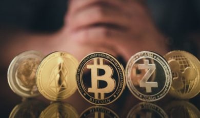 Man's Folded Hands Behind 5 Gold Coins of Cryptocurrency