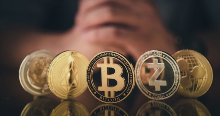Man's Folded Hands Behind 5 Gold Coins of Cryptocurrency