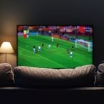 Soccer Game Plays on TV In Front of Empty Couch Inside Living Room